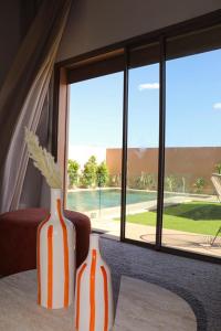 deux vases assis sur une table devant une fenêtre dans l'établissement Villa Alma, luxueuse villa au cœur de Marrakech, à Marrakech