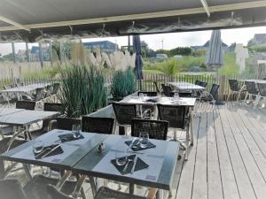 - un ensemble de tables et de chaises sur une terrasse dans l'établissement Arlette, à Ouistreham
