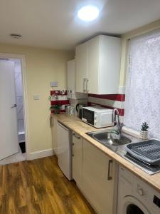 uma pequena cozinha com um lavatório e um micro-ondas em Experience Downing Road Dagenham 2 bedroom Apartment em Dagenham