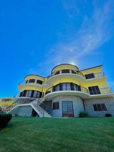 a large yellow and white building with a green lawn at LouriVillage in Lourinhã