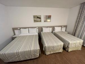 duas camas num quarto de hotel com lençóis brancos em Atibaia Residence Hotel & Resort em Atibaia