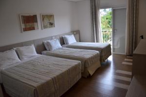 two beds in a hotel room with a window at Atibaia Residence Hotel & Resort in Atibaia