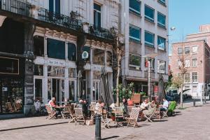 un grupo de personas sentadas en mesas en sillas en una calle de la ciudad en Vakantielogies Faja lobi, en Gante