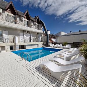 a swimming pool with white lounge chairs next to a building at Hotel Tirol D'andrea in Villa General Belgrano