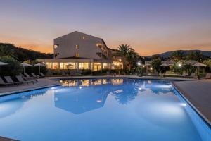 a large pool with blue water in front of a building at Livadi Nafsika Hotel in Dassia