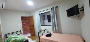 a room with a bed and a tv on the wall at Casa do Victor in Vassouras