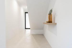 a hallway with a white wall with a shelf and a plant at Beautiful 4BR Family home with Patio and Parking! in Perth