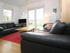 a living room with a black leather couch and a table at Cottage on the Kummerower See, Kummerow in Kummerow