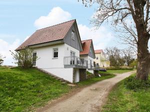 una casa blanca con techo negro y un camino de tierra en Cottage on the Kummerower See, Kummerow, en Kummerow