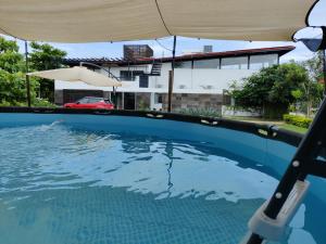 a swimming pool with an umbrella in front of a house at Casa Ilhe Ha in Santa María Tonameca