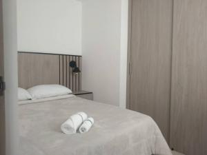 2 toallas blancas en una cama blanca en un dormitorio en Acogedor apartamento con sala de TV, en Sabaneta