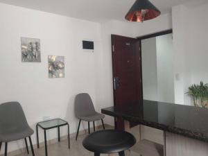 una cocina con encimera negra y taburetes en Acogedor apartamento con sala de TV, en Sabaneta