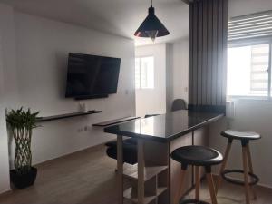 sala de estar con mesa, taburetes y TV en Acogedor apartamento con sala de TV, en Sabaneta