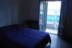 1 dormitorio con cama azul y balcón en Lunfardo Boquense en Buenos Aires