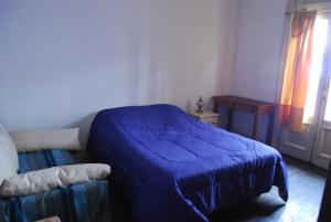 sypialnia z niebieskim łóżkiem i oknem w obiekcie Lunfardo Boquense w BuenosAires