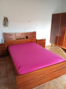 a bedroom with a large wooden bed with pink sheets at house FYNTIKAKH - SKALA in Anopoli Sfakion