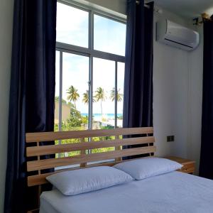 a bedroom with a bed and a window with palm trees at Shitha Inn in Hithadhoo