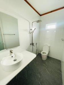 Baño blanco con lavabo y aseo en Shitha Inn en Hithadhoo
