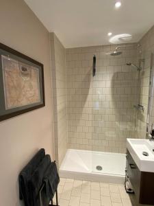 a bathroom with a shower and a tub and a sink at Tasteful 2BD Flat wOpen Plan Living - Blackheath! in London