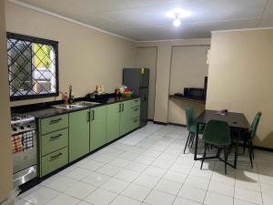 a kitchen with green cabinets and a table with chairs at Osso fu mi ati (huis van mijn hart) in Paramaribo