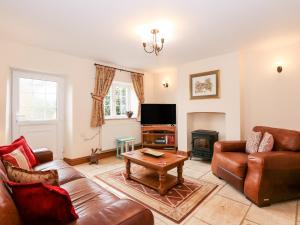 a living room with leather furniture and a fireplace at Kath's Cottage in Heacham