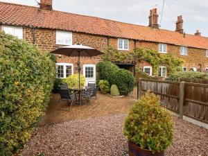 a patio with a table and chairs and an umbrella at Kath's Cottage in Heacham