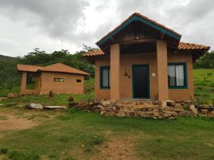 a small house with a stone wall in the yard at Pousada Fazenda Vitoria in São João Batista do Glória