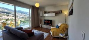 uma sala de estar com um sofá e uma televisão em Highrise Madalenas Apartment no Funchal