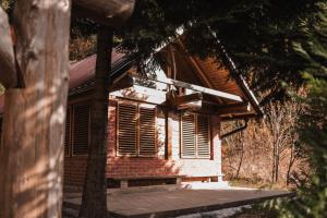 una pequeña casa de ladrillo con un porche y un árbol en Vikendica MINI en Jotanovići