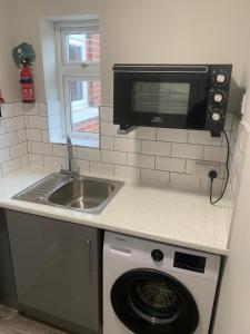 a kitchen with a sink and a microwave and a washing machine at Matipa-Given Apartments Eastleigh Southampton in Eastleigh