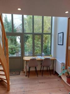 a room with a table and two chairs and windows at La Mascotte - Votre refuge bergeracois in Bergerac