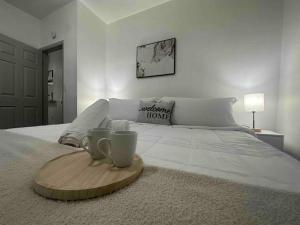 Una cama con una bandeja de madera con dos tazas. en 2 KING Beds, W/D, Parking, Stylish & GREAT VALUE, en Schenectady