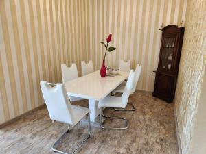 a white table with white chairs and a vase with a red flower at Apartment 16, Im Zentrum von Braunlage in Braunlage