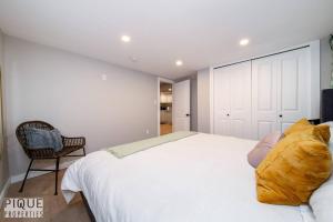 - une chambre avec un grand lit blanc et une chaise dans l'établissement Modern Urban Escape -King Bed -Pet Friendly - Free Parking & Netflix - Fast Wi-Fi, à Edmonton