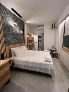 a bedroom with a white bed and a brick wall at The MITS luxury apartments in Skiathos