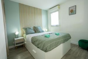 a bedroom with a bed with blue pillows and a window at Le Zéphyr - Tout équipé - Wifi - Parking gratuit in Saint-Nazaire