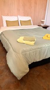 1 cama grande con 2 almohadas amarillas. en Casa Vino Andino en La Consulta