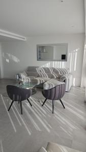 een woonkamer met een bank, 2 stoelen en een tafel bij Ático lujo OASIS in Estepona
