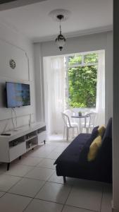 uma sala de estar com um sofá, uma televisão e uma mesa em 3 quartos Copacabana no Rio de Janeiro