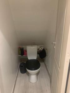a small bathroom with a toilet with a black seat at Charmante petite maison in Maubeuge
