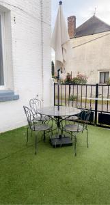 una mesa con sillas y una sombrilla en el césped en Charmante petite maison, en Maubeuge