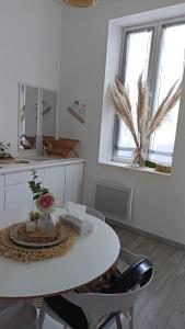 comedor blanco con mesa y 2 ventanas en Charmante petite maison, en Maubeuge