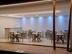 uma sala de jantar com mesas e cadeiras e uma parede branca em Premium Hotel em Delmiro Gouveia