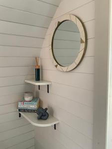 a mirror on a wall with shelves and books at Secluded Cosy Luxury Pod in Shrewsbury
