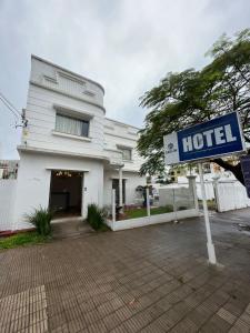 a hotel sign in front of a white building at BARLOS HOTEL in Uruguaiana