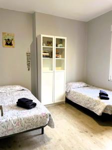 1 dormitorio con 2 camas y estante para libros en La Penca del Maguey en Santander