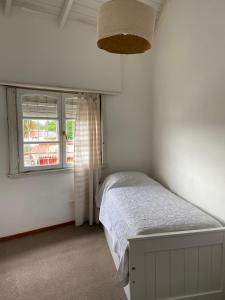 Habitación blanca con cama y ventana en Casa en alquiler TANDIL - Lamadrid en Tandil