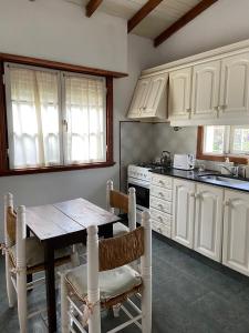 坦迪爾的住宿－Casa en alquiler TANDIL - Lamadrid，厨房配有白色橱柜和一张带椅子的木桌