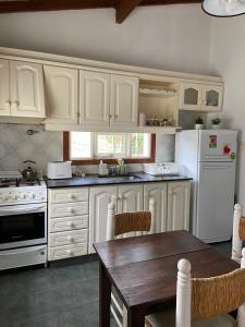 坦迪爾的住宿－Casa en alquiler TANDIL - Lamadrid，厨房配有白色橱柜和木桌