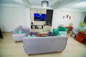 ein Wohnzimmer mit einem Sofa, Stühlen und einem TV in der Unterkunft Moderno y acogedor departamento in Tacna